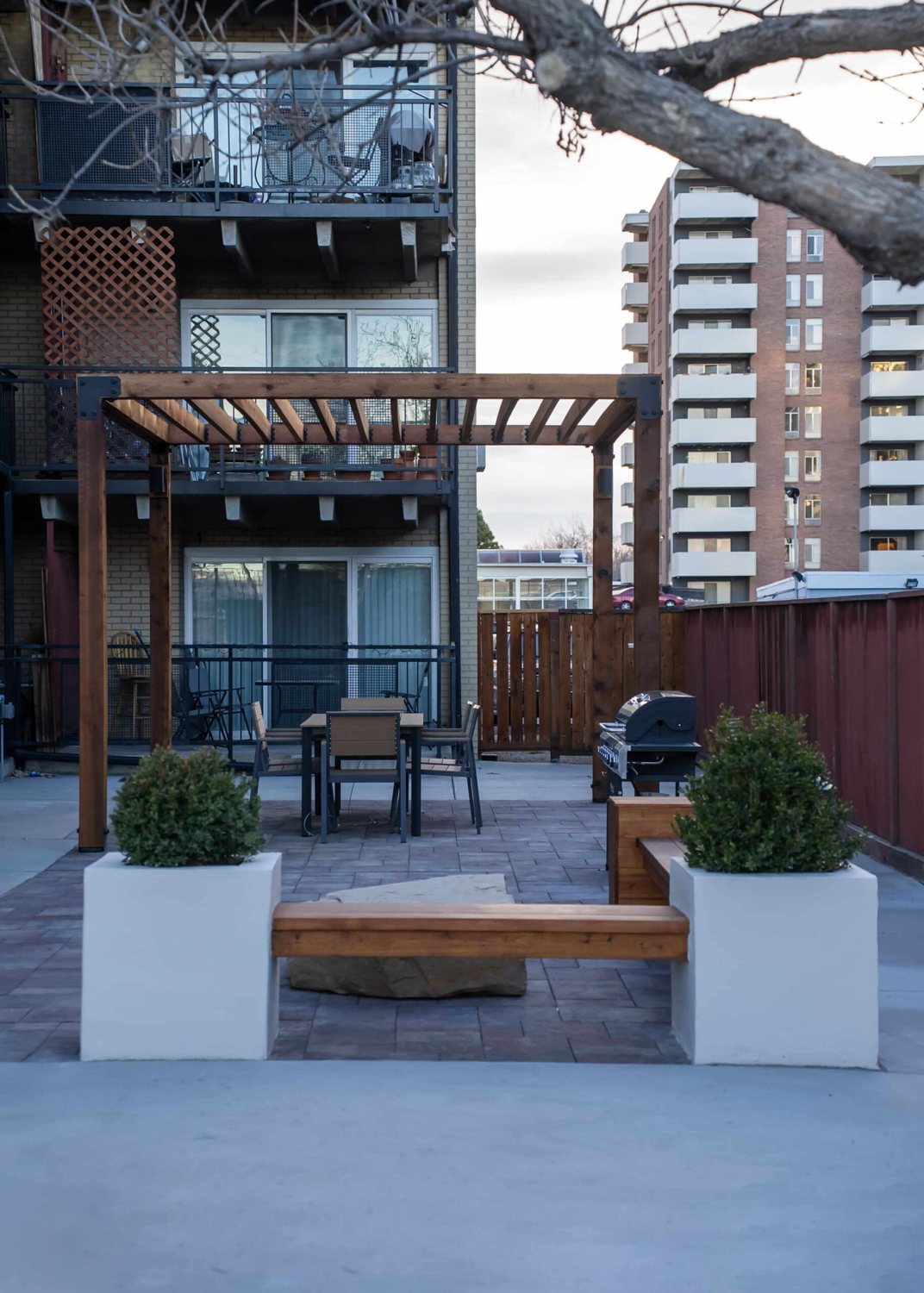 Multifamily courtyard with cedar pergola, planters and lawn beside the building