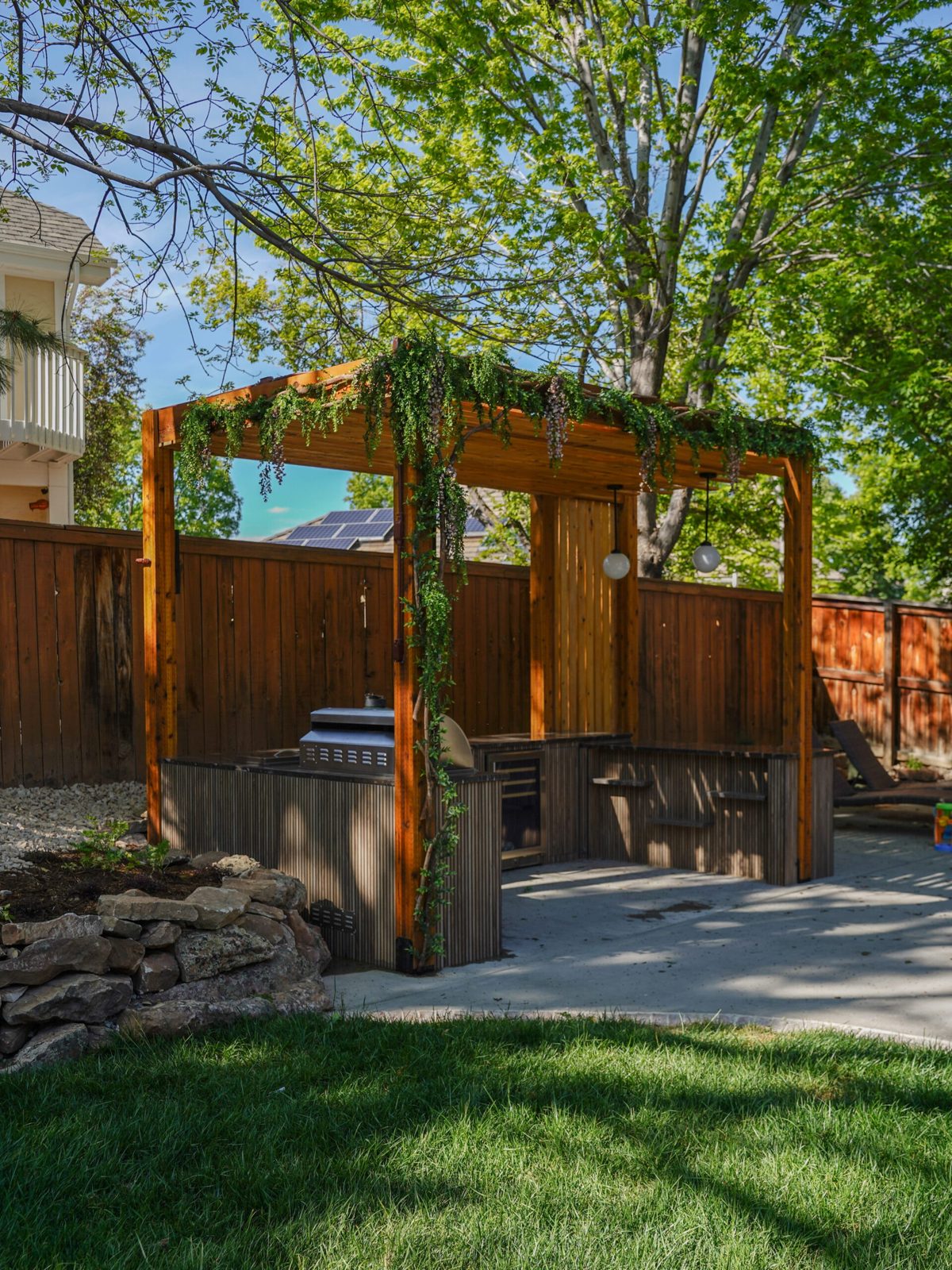 Cedar pergola with hanging swing chairs beside a putting green