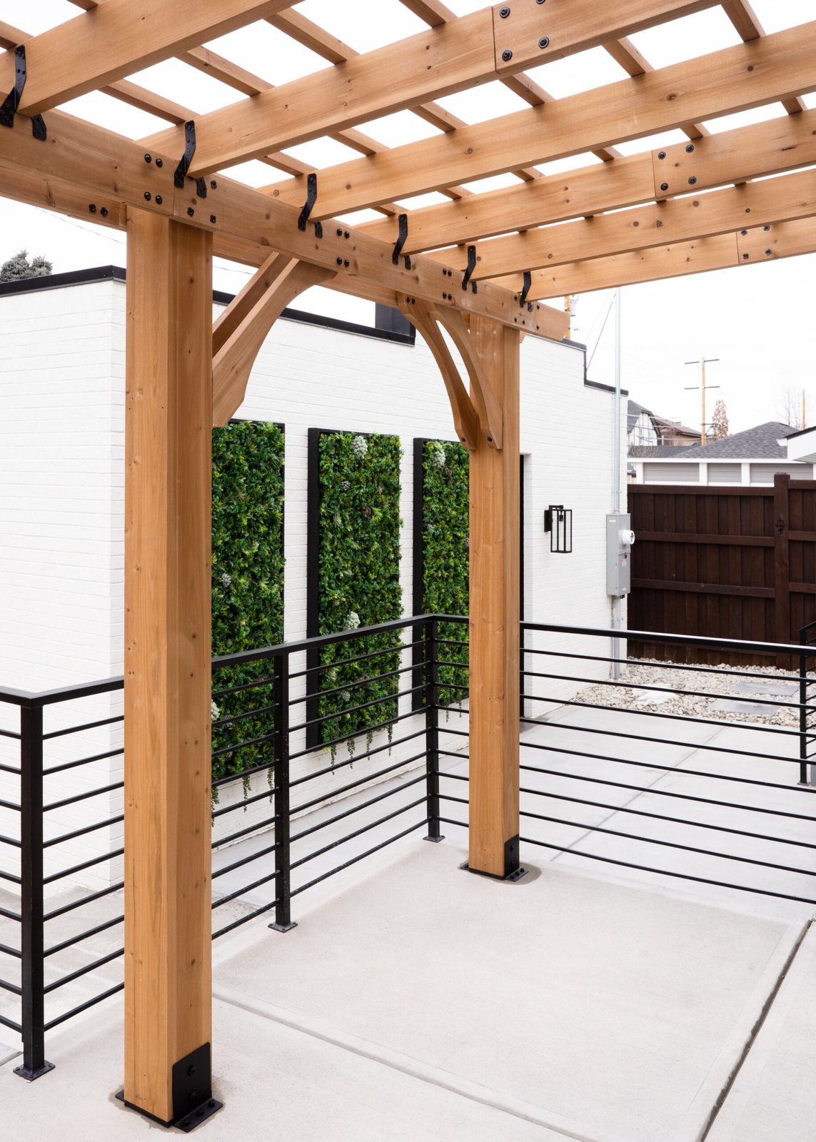 Modern timber pergola with black architectural railing beside living walls